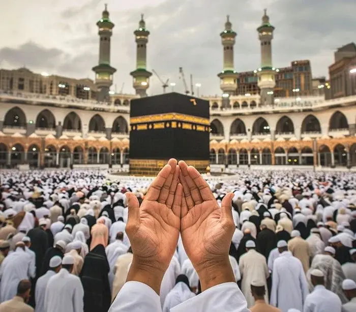 Pilgrim raising hands in dua while facing the Kaaba at Masjid al-Haram